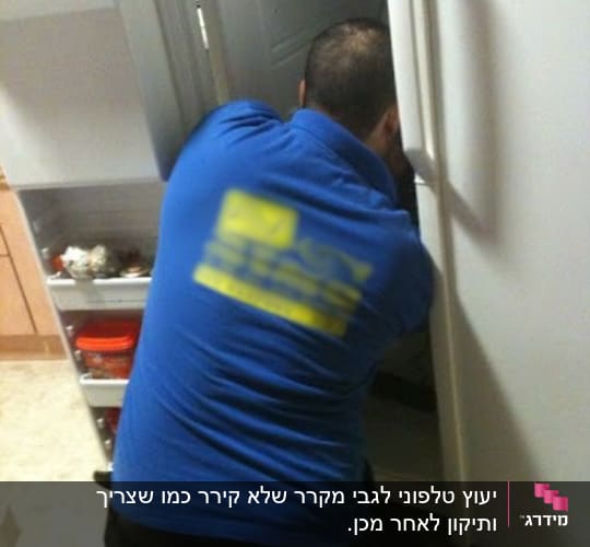 טכנאי מקררים עובד על תיקון מקרר פתוח
